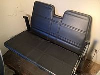 Front view showing black vinyl bench seat with two headrests and armrests.