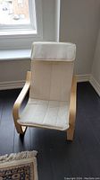 Front view of the child's chair showing white fabric seat and backrest with wooden frame.