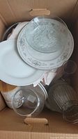 Top view of a box containing glass bowls, plates, and drinking glass showing mixed glassware items.