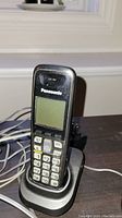 Panasonic cordless phone in a compact charging cradle with visible keypad and LCD screen.