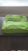 Top angled view of green Samsonite tote bag showing front zippered pocket and handles.