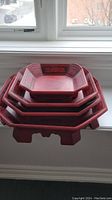 Stacked view of five reddish-brown octagonal wooden trays with black painted edge details and elevated feet.