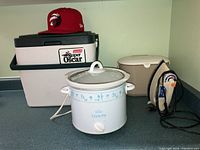 Full view of the lot including the Rival Crock-Pot, iron, cooler box, and Raptor's cap on countertop.
