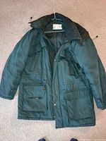 Dark green winter coat with multiple front pockets and button closure