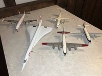 Overview of five vintage vacuum formed plastic scale airplane models on table: Lockheed Constellation, BAE Concorde, Air UK Bae 146, RCAF North Star DC-4, and BEA Viscount.
