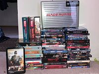 Full overview of the movie collection showing stacked Blu-Rays and DVDs with Blade Runner metal briefcase on top and Sky Sharks tin case in front.