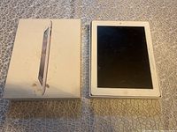 Apple iPad model A1395 with white front bezel and damaged screen next to original box