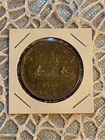 Reverse side of the 1951 Canadian silver dollar showing the canoe with two voyageurs and date 1951 with lettering.