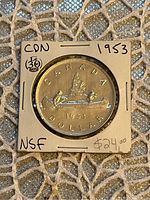 Front side of the 1953 Canadian silver dollar showing the voyageur and canoe design with inscriptions.