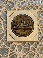 Reverse side of the 1956 Canadian silver dollar showing canoe design with two men and the year 1956.