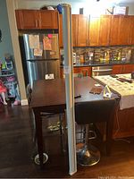 Full view of the projector screen standing upright in a kitchen area showing its length and aluminum casing.