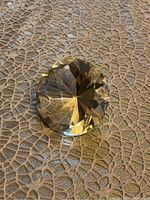 Crystal diamond paperweight resting on textured surface showing facets and light refraction.
