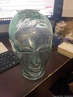 Front view of vintage human-sized glass head sculpture showing detailed facial features and textured hair.
