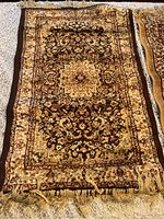 First Persian praying mat rug with detailed central medallion in dark brown and gold tones with fringed ends.