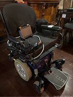 Three-quarter front view showing seat, joystick controller, front suspension and footplate