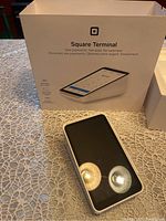 Front view of Square Terminal device next to original packaging box