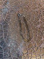 Full view of the sterling silver chain link bracelet laid out on a textured surface showing the entire length and design.