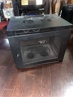 Closed front view showing mesh door with Tripp-Lite logo, ventilation fans on top, placed on wooden floor.