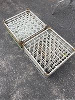 Two commercial dishwasher glass racks on asphalt ground, one full of champagne glasses and one empty