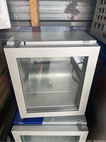 Front view of the compact mini fridge showing glass door and interior shelf