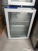 Front view of glass door with white frame, showing interior and wire shelves