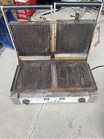 Front view of the used Eurodib double panini press showing ribbed grill plates and adjustable knobs