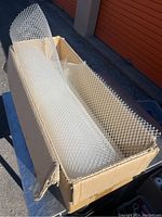 Two white plastic mesh liner rolls inside a cardboard box.