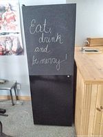 Full front view of the Koolspace wine cellar featuring a black chalkboard painted front door with 'Eat, drink and be merry' chalk writing.