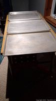 Three aluminum baking sheets stacked on top of one another, showing full view of surfaces.