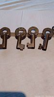Four round brass keys laid out horizontally showing circular heads with markings including 'S' and railway initials.
