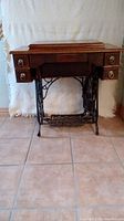 Full view of the antique New Williams sewing machine cabinet with 5 drawers and refinished wood surface.