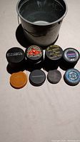 Top view of eight hockey pucks and metal bucket showing different puck logos and types.