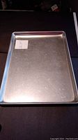 Top-down view of the aluminum baking sheet showing rectangular flat surface with raised edges and a white sticker labelled Lot 75.