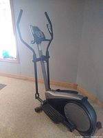 Full view of elliptical trainer showing black and silver frame, dual handlebars, and foot pedals