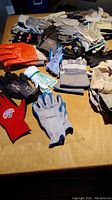 Overview of assorted work gloves and chamois on a table, showing various colors and materials.