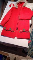 Front view of red Hudson's Bay wool coat with decorative pattern at bottom and hood lined with faux fur trimmed opening.