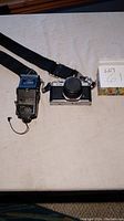 Camera body with neck strap and attached flash unit showing overall items included.