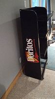 Side view of black metal shelving unit with large Doritos logo on the side panel.