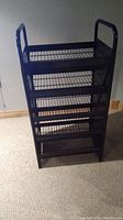 Full frontal view of the shelving unit showing 5 wire mesh shelves and tubular metal frame