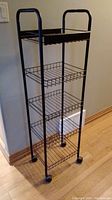 Full front view of the 5-shelf metal storage unit on casters against wall. Shows height and design details.