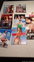 Photo displaying assorted Victoria's Secret catalogs from various years alongside Sports Illustrated Swimsuit editions.