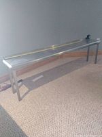 Full side-angle view of stainless steel shelf showing length with measuring tape along top surface.