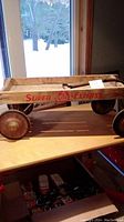 Side view of the antique wooden child’s wagon showing 'Super Express' lettering and metal wheels with some rust.