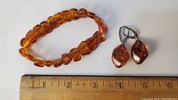 Amber bracelet and teardrop amber earrings with a ruler for size reference.