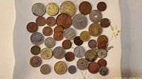 Full view of approximately 40 assorted coins of various sizes, metals, and designs spread out on a surface.