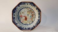 Full view of octagonal Chinese famille rose and blue and white plate showing central scene and border detail.