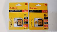 Front view of two unopened Kodak microSDHC memory cards in yellow packaging showing 16GB and 32GB capacities, speed ratings, and included adapters.