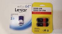 Front view of Lexar 64GB JumpDrive and generic 32GB USB 2.0 package with two black and orange USB flash drives.