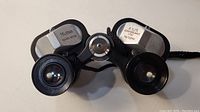 Top-down view of Telesar binoculars showing eyepieces and labels: 6x25 coated optics, extra wide angle 11 30'