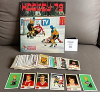Photo showing the Panini Hockey '79 sticker album propped up with multiple hockey stickers in front, displaying the style and quantity of stickers included.